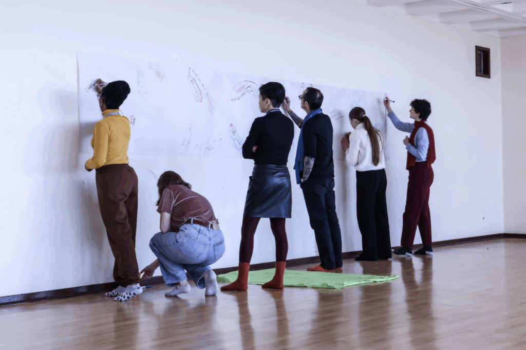 a group of workshop participants writing on butcher’s paper pasted on the wall mapping their journey to this workshop