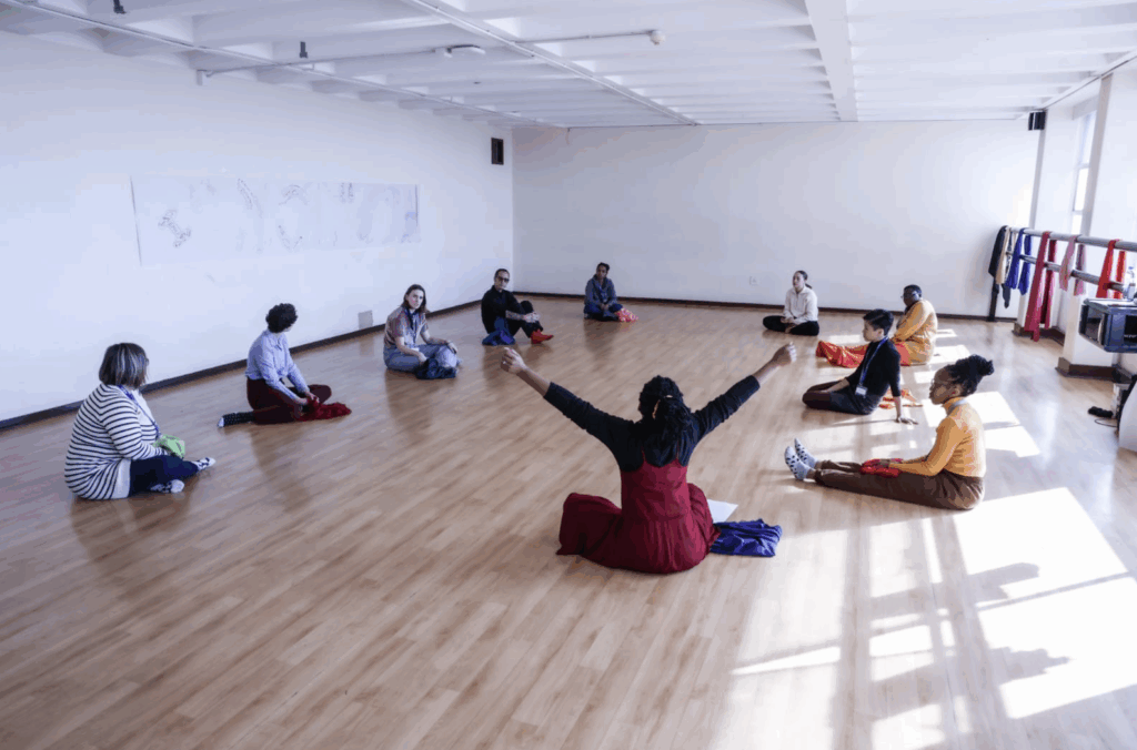 workshop participants sitting on the floor around Linda
